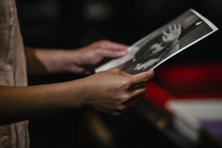 A close-up view of hands holding a black and white photo, emphasizing the texture and depth.