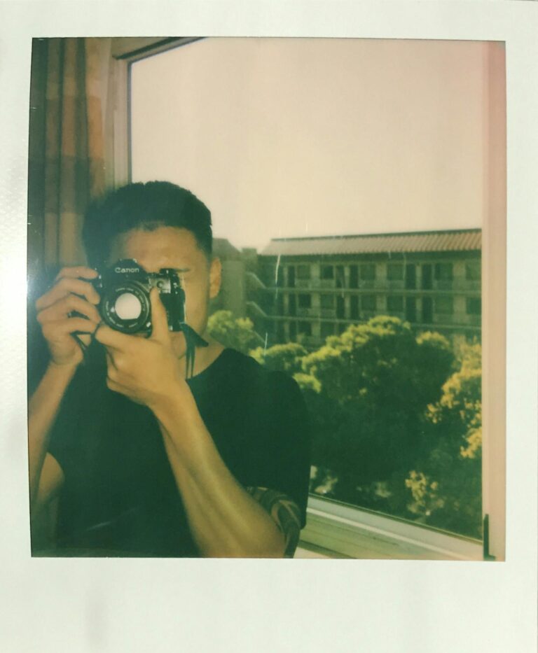 A person capturing an image with an analog camera by a window, creating a vintage feel.