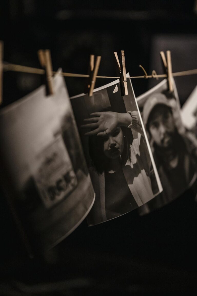 Black and white photos hanging in a darkroom with a moody artistic atmosphere.