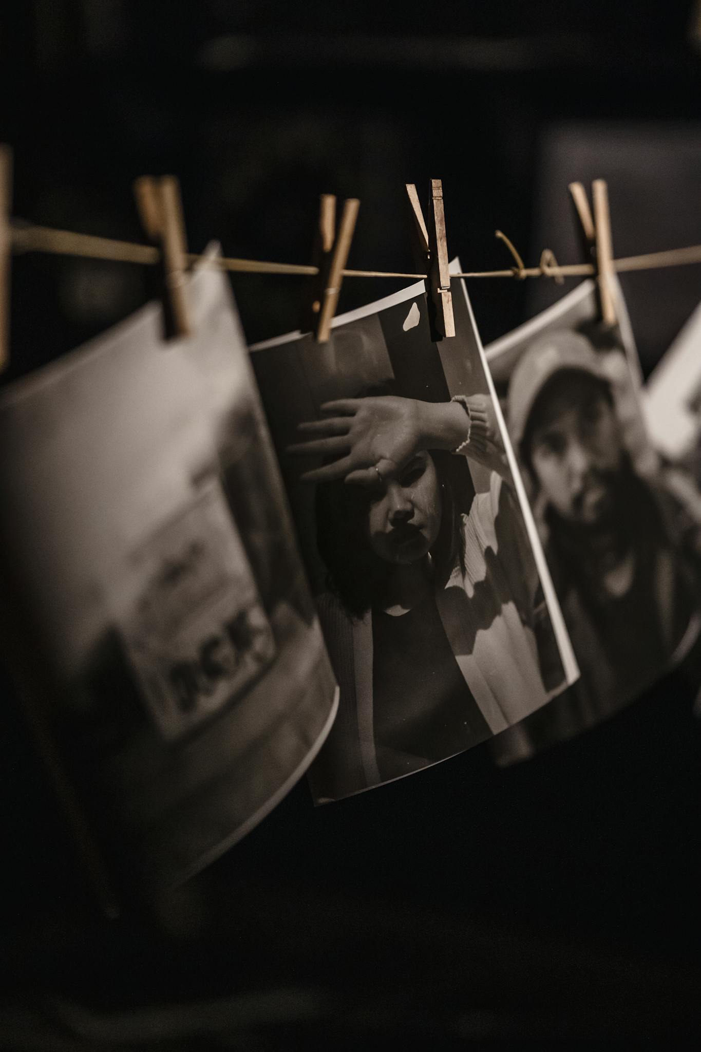 Black and white photos hanging in a darkroom with a moody artistic atmosphere.